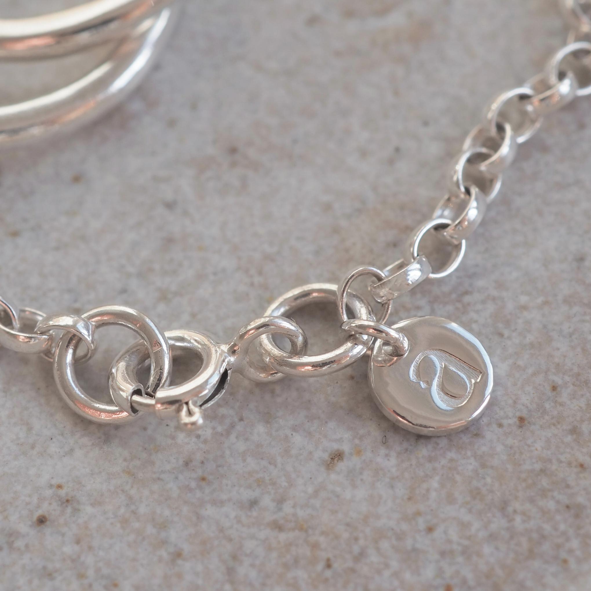 Detailed view of the Halo Bracelet clasp with charm stamped with the aujune logo