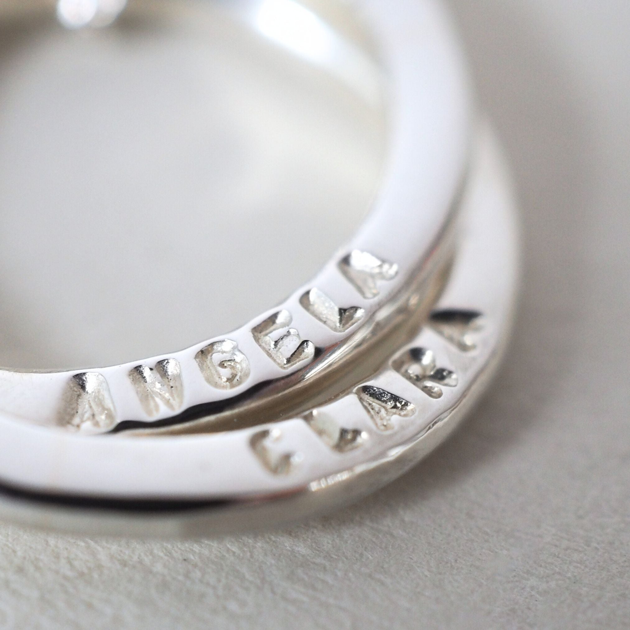 Close up of hand-stamped names on a personalised sterling silver  necklace