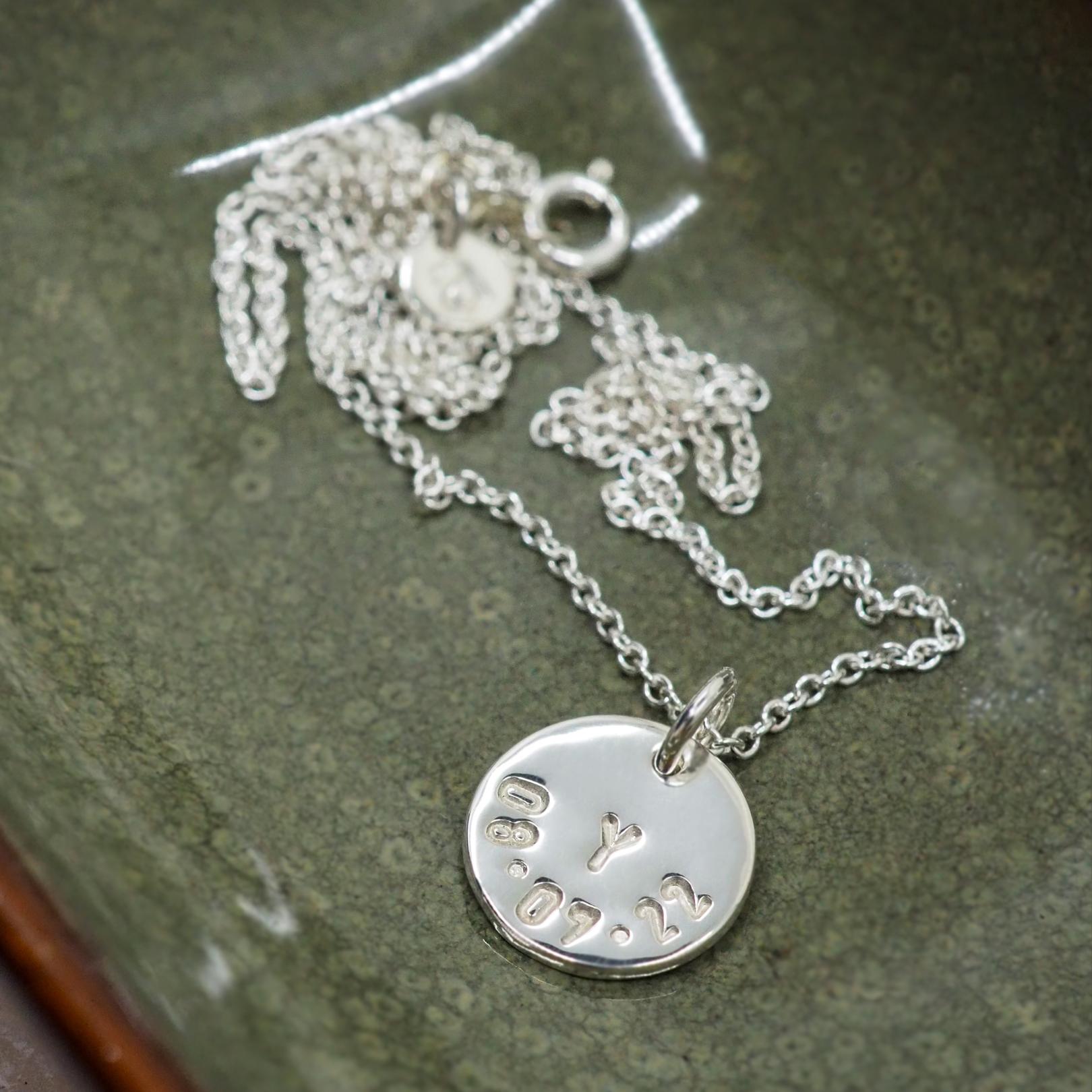 Personalised initial and date disc necklace in a jewellery dish