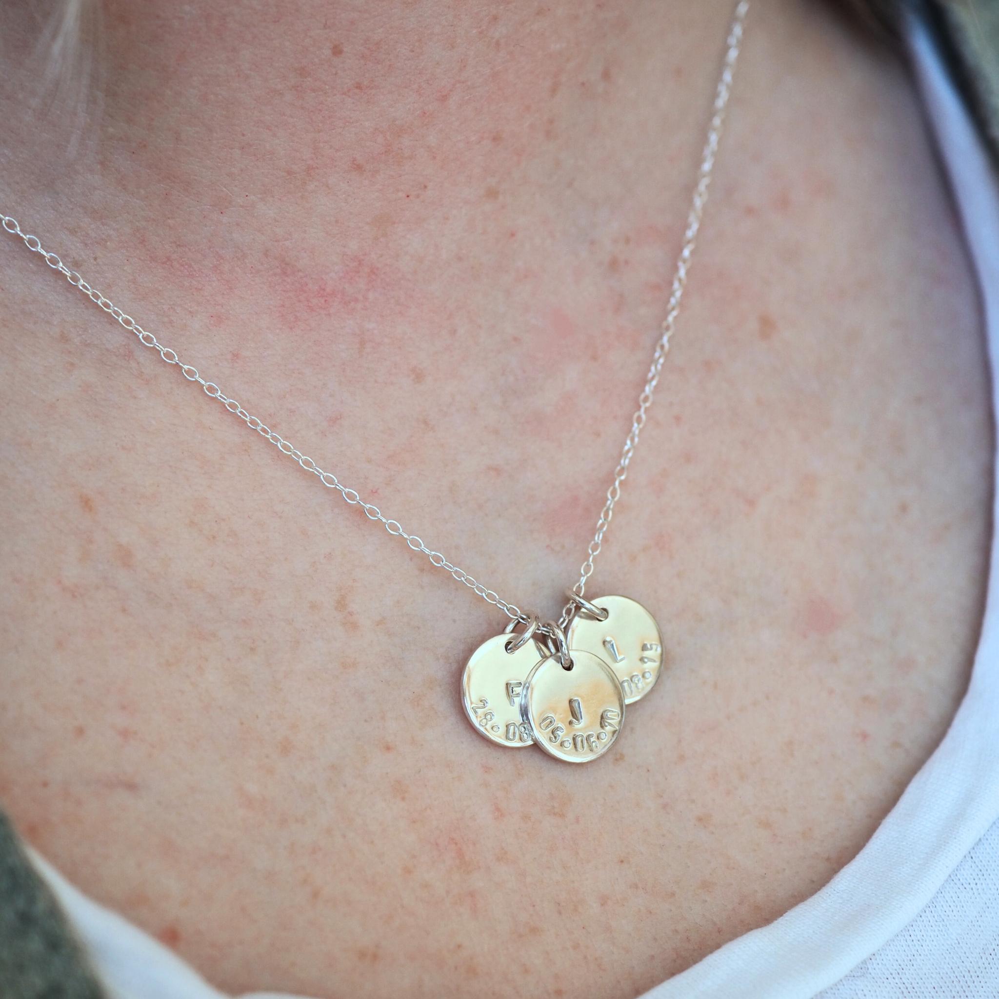 Model wearing a triple initial and date disc necklace in sterling silver