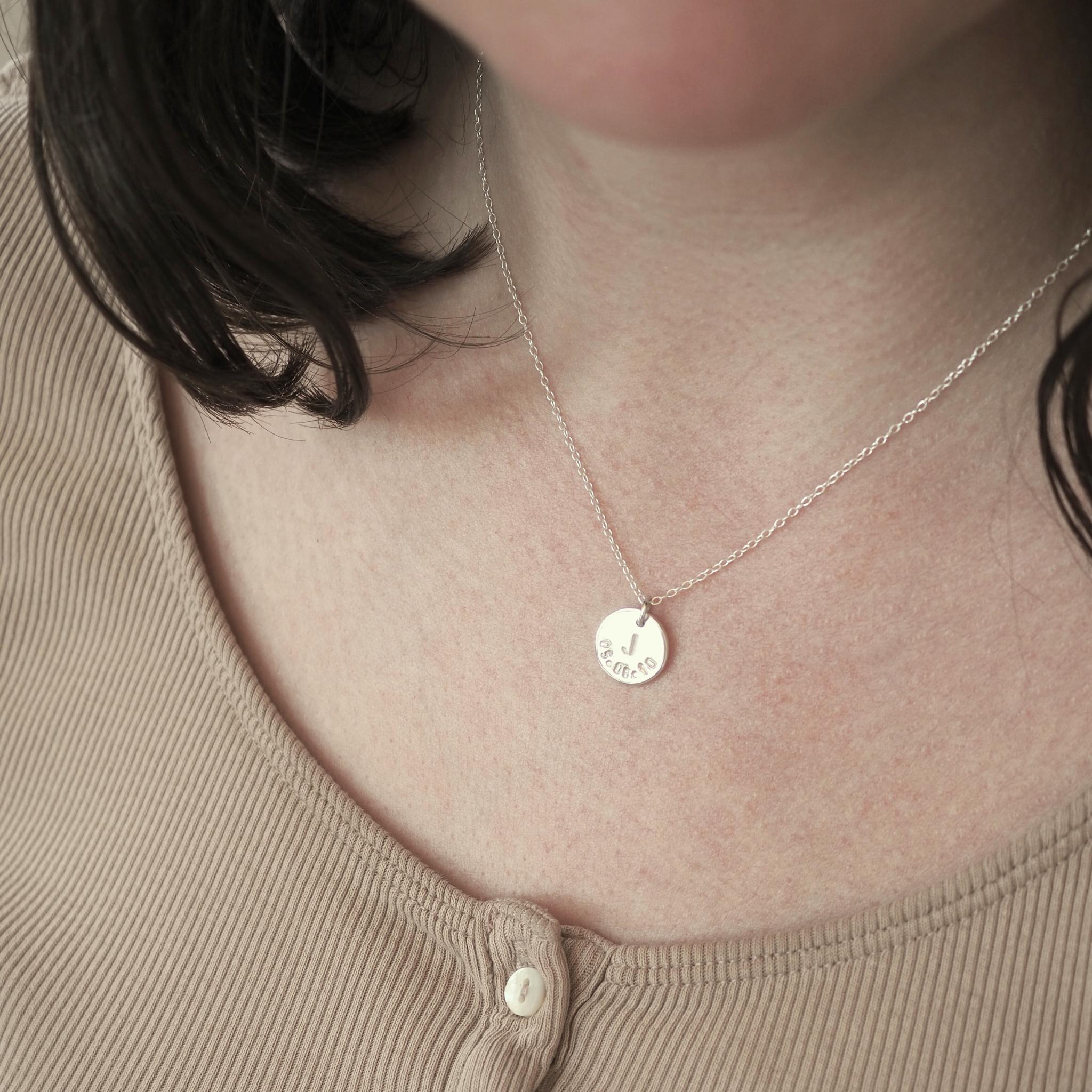 Model wearing a custom initial and date necklace in sterling silver