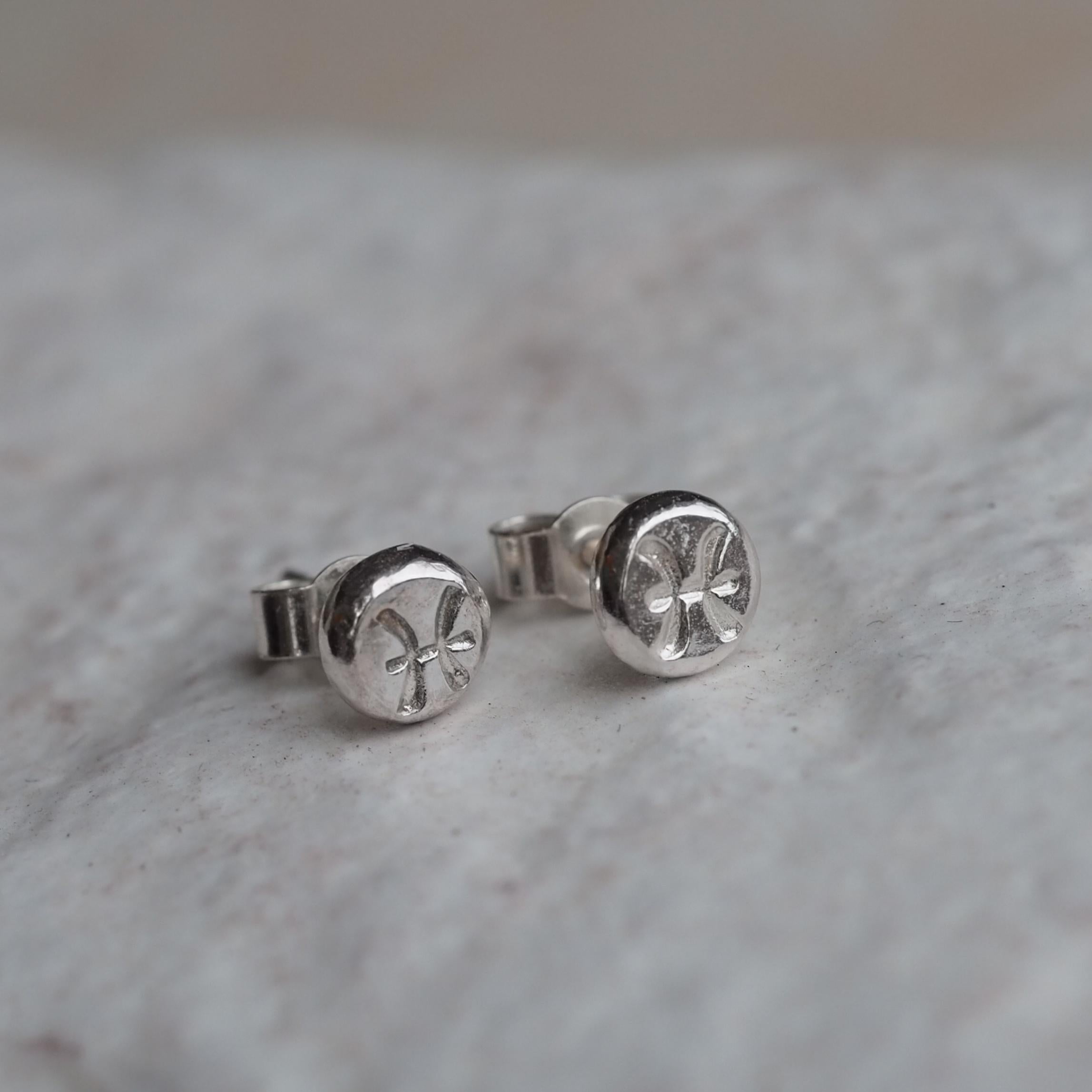 Close-up of Organic Zodiac Stud Earrings in Sterling Silver, featuring hand-stamped astrological symbols with a textured finish.