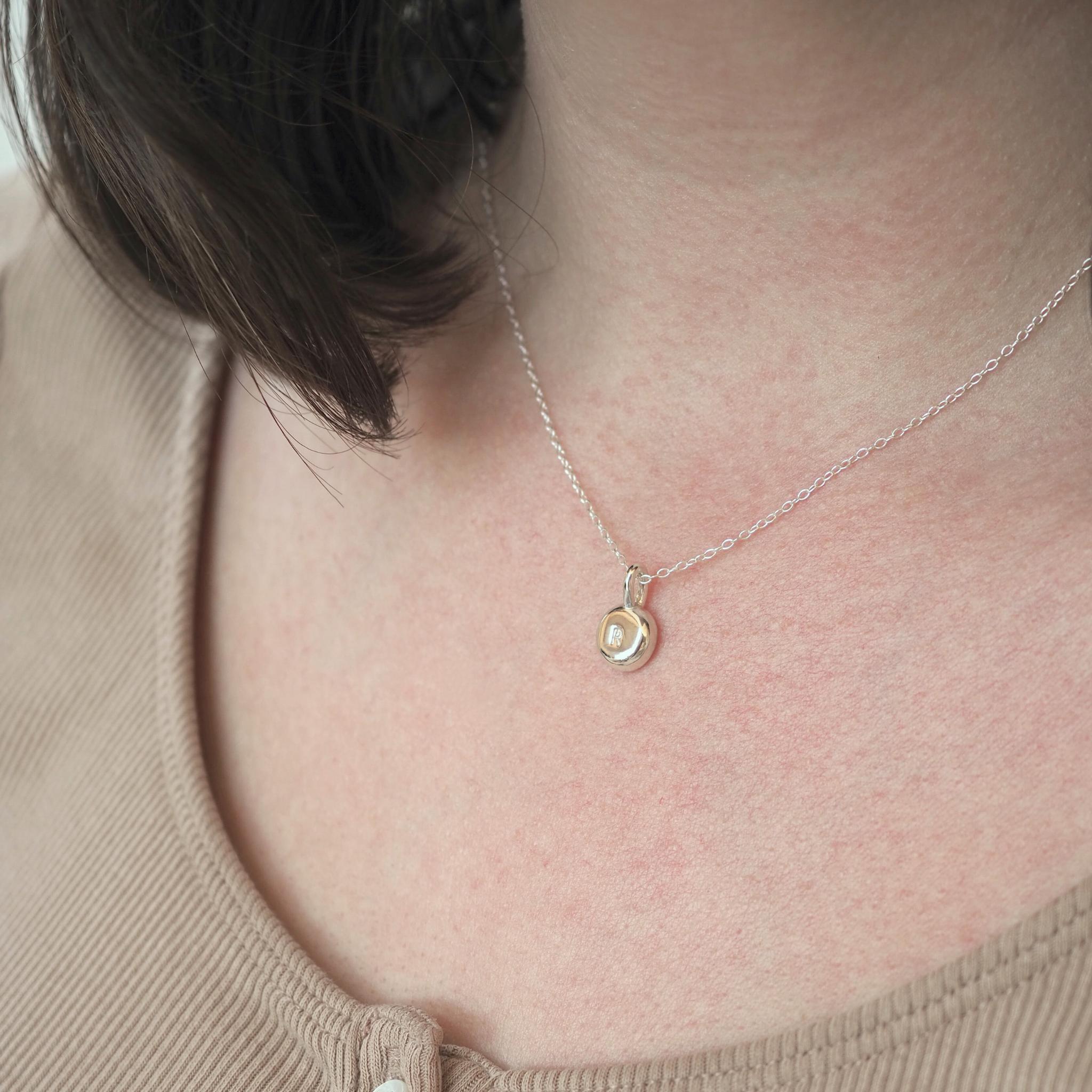 Personalised molten pebble necklace in sterling silver with hand-stamped initial